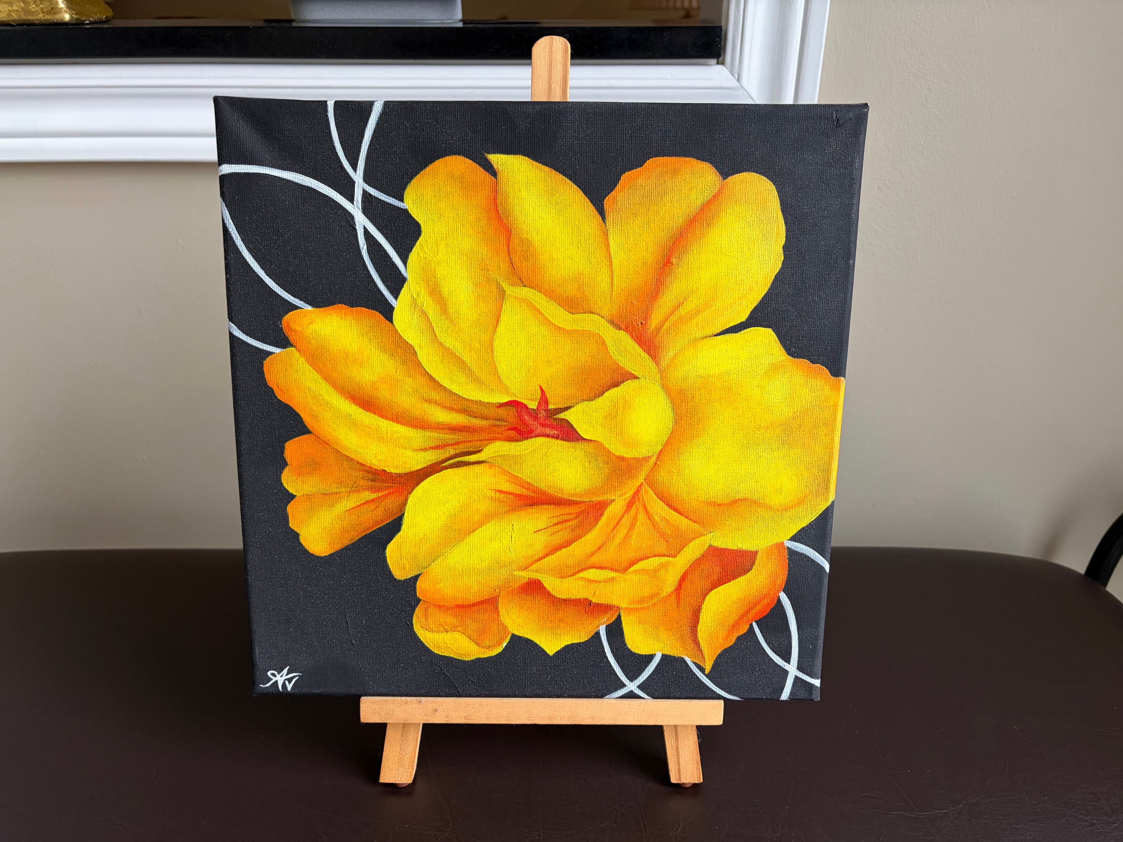A yellow flower painting displayed on a small easel.